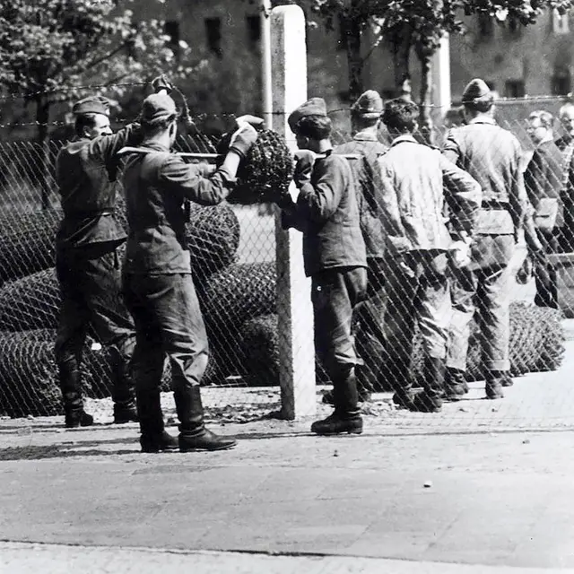 Grenzpolizisten errichten am 13. August 1961 an der Sektorengrenze zu West-Berlin einen Zaun aus Betonpfosten, Maschen- und Stacheldraht. | IMAGO / UIG DDR-Grenzpolizisten errichten Maschendrahtzaun mit Stacheldraht an Sektorengrenze in Berlin, August 1961.