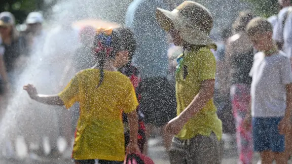 Kinder kühlen sich an einem Wassersprenger ab | picture alliance/Sven Hoppe Kinder kühlen sich an einem Wassersprenger ab