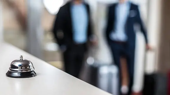 Ab Oktober wird unter anderem in Hotels in Kiel eine Übernachtungssteuer fällig. Die Betreiber müssen sie in einem händisch ausgefüllten Formular an die Stadt übermitteln. | Colourbox, - Eine männliche Hand betätigt eine Klingel an einer Hotelrezeption.