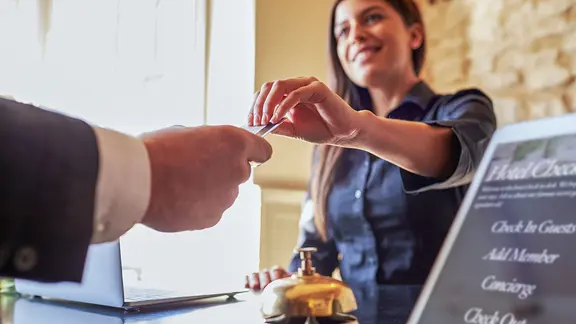 Eine Hotelangestellte überreicht einem Gast seine Zimmerkarte. | Colourbox Eine Hotelangestellte überreicht einem Gast seine Zimmerkarte.
