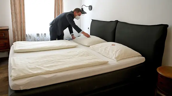Ein Mitarbeiter eines Hotels legt eine Süßigkeit auf ein Hotelbett. | dpa picture alliance/APA, Barbara Gindl Ein Mitarbeiter eines Hotels legt eine Süßigkeit auf ein Hotelbett.