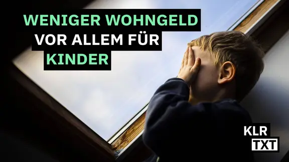 Ein kleiner Junge steht am Fenster und hält sich die Hände vor sein Gesicht.