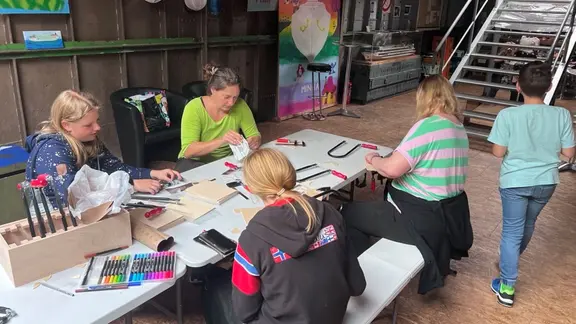 Jeden Mittwoch ist das Kulturschiff "MINNA" Treffpunkt für Kinder und Jugendliche aus Boizenburg. | NDR, Lucie Kluth Zwei Mädchen und zwei Frau sitzen am Tisch und arbeiten mit der Laubsäge.