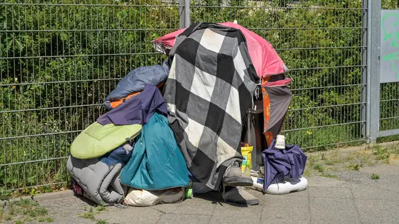 Ein Obdachloser schützt sich gegen die Sonne mit Decken | IMAGO / Joko Ein Obdachloser schützt sich gegen die Sonne mit Decken