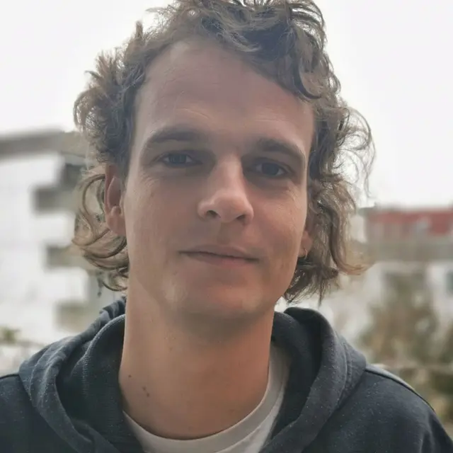 Dr. Peter Pfleiderer | P. Pfleiderer Porträt von jungem Mann mit lockigen Haaren, freundlich neutraler Blick in Kamera