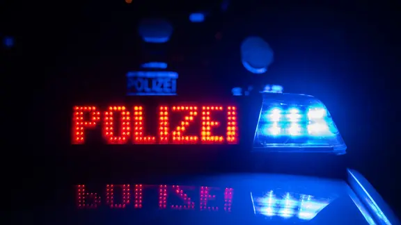 Zwei Polizisten stehen vor einem Polizeifahrzeug.
