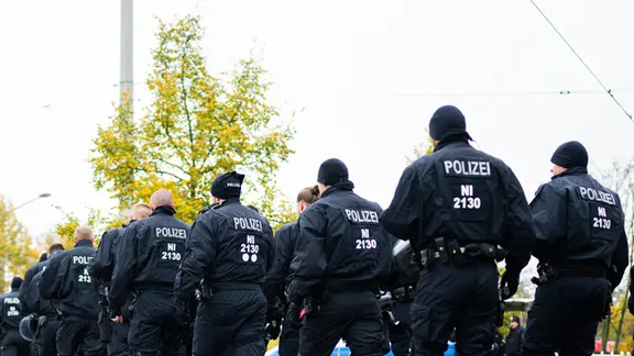 Polizeibeamte gehen vor dem Stadion in Hannover. | picture alliance, Noah Wedel Polizeibeamte gehen vor dem Stadion in Hannover.