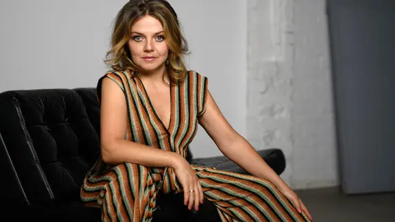 Schon ihr Debüt-Album "Bohème" bringt Annett Louisan 2004 den Durchbruch. Am 11. September erscheint ihr neues Werk "Sehnsucht". | Jennifer Weyland Photography Annett Louisan sitzt auf einem schwarzen Sofa, trägt einen gestreiften, ärmellosen Overall und blickt ruhig und direkt in die Kamera.