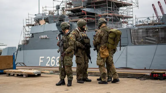 Feldjäger der Bundeswehr stehen auf der Blohm und Voss Werft vor einer Korvette | NDR/Elias Bartl Feldjäger der Bundeswehr stehen auf der Blohm und Voss Werft vor einer Korvette