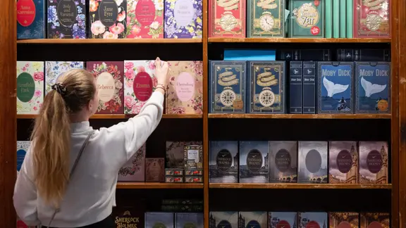 Eine Frau nimmt ein Buch aus einem Regal am Messsestand des Verlags Coppenrath. 2024 | picture alliance/dpa | Boris Roessler Eine Frau nimmt ein Buch aus einem Regal am Messsestand des Verlags Coppenrath. 2024