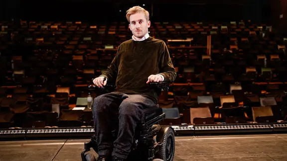 Seine Querschnittelähmung hielt Samuel Koch nicht davon ab, ein erfolgreicher Schauspieler zu werden. | picture alliance/dpa | Uwe Anspach Der Schauspieler Samuel Koch steht mit seinem Rollstuhl auf einer Theaterbühne