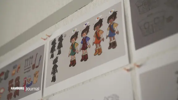 Innerhalb von drei Jahren mussten sie immer wieder viele kleinteilige Arbeitsschritte machen. | Screenshot NDR Mehrere Figuren ausgedruckt auf einem Blatt Papier, das an eine Wand gepinnt ist.