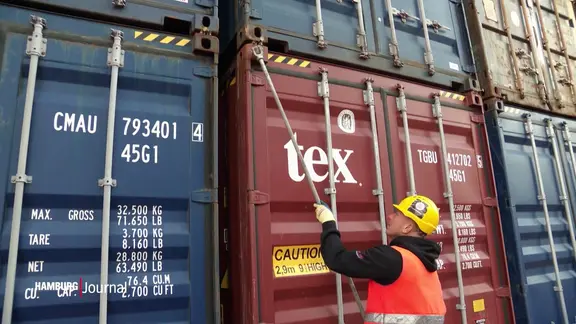 Ein Hafenarbeiter öffnet einen Überseecontainer.