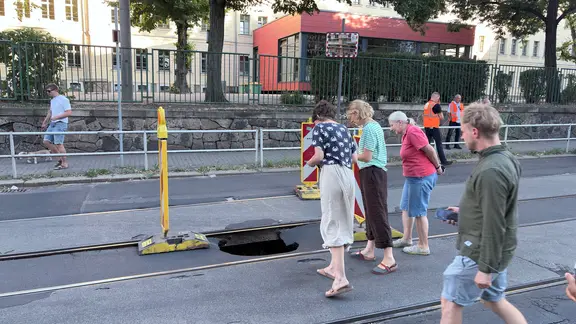 Mehrere Menschen schauen auf einer Straße in ein Loch zwischen Straßenbahngleisen. | news5/Christian Grube Mehrere Menschen schauen auf einer Straße in ein Loch zwischen Straßenbahngleisen.