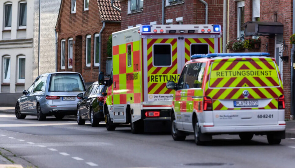 Zwei gelb-rot karierte Rettungsdienstfahrzeuge stehen auf einer Straße zwischen Wohnhäusern.