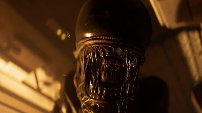 Nahaufnahme des bedrohlichen Xenomorph-Kopfes aus Alien Isolation, mit offenem Maul und scharfen Zähnen in dunkler, orange beleuchteter Umgebung.