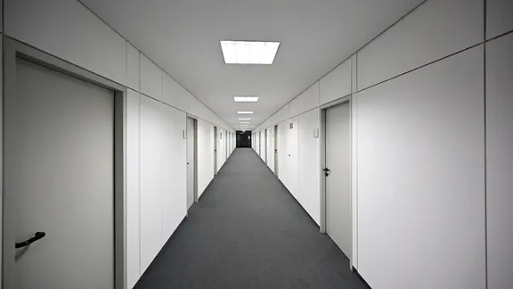 Ein leerer Flur in einem Bürogebäude. | imago images / Funke Foto Services Ein leerer Flur in einem Bürogebäude.