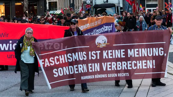 Demonstrierende versammeln sich in Hamburg hinter einem Transparent auf dem steht "Faschismus ist keine Meinung, sondern ein Verbrechen". | dpa/Marcus Golejewski Demonstrierende versammeln sich in Hamburg hinter einem Transparent auf dem steht "Faschismus ist keine Meinung, sondern ein Verbrechen".