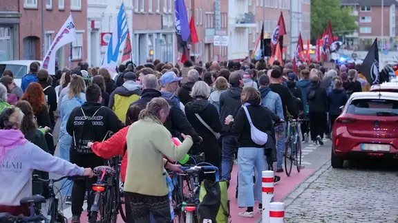 In Kiel sind rund 380 Menschen nach den ersten Hochrechnungen der Landtagswahl in Sachsen-Anhalt auf die Straße gegangen. | Daniel Friederichs Eine Menschenparade mit Fahnen läuft durch die Straßen