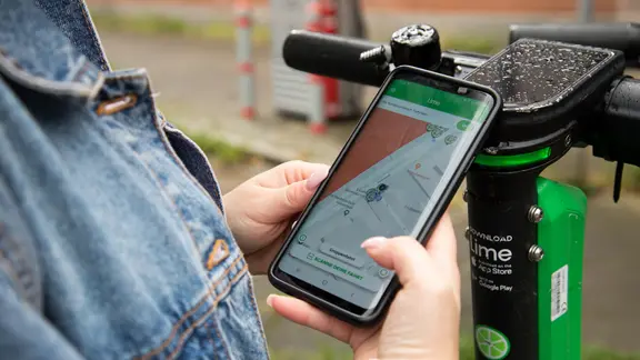 Eine Frau leiht sich in Hamburg mit einer App auf ihrem Handy einen E-Roller aus. | picture alliance / dpa Themendienst | Christin Klose Eine Frau leiht sich in Hamburg mit einer App auf ihrem Handy einen E-Roller aus.