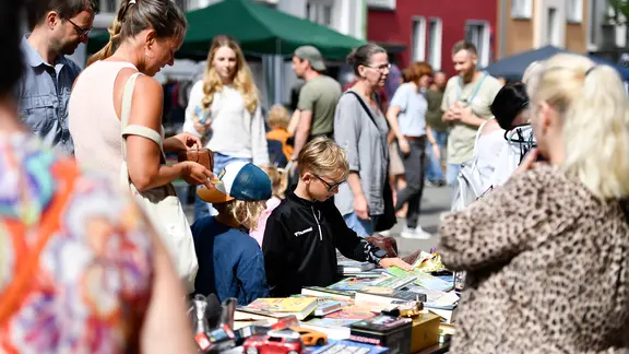 Kinder und Erwachsene sind auf einem Flohmarkt bei Sommerwetter unterwegs. | IMAGO / Funke Foto Services Kinder und Erwachsene sind auf einem Flohmarkt bei Sommerwetter unterwegs.