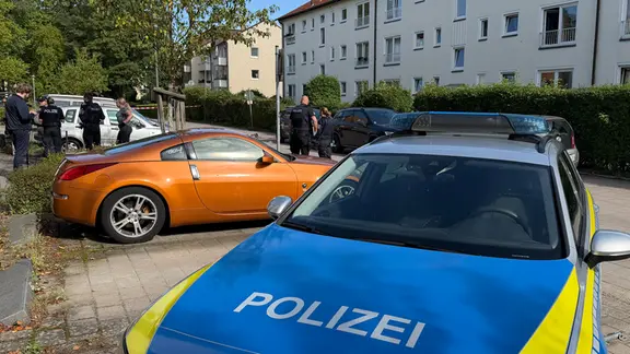 Die Einsatzkräfte wurden kurz vor 10 Uhr alarmiert. | René Schröder Ein Polizei-pkw in einem Wohngebiet im Vordergrund, dahinter Polizist*innen