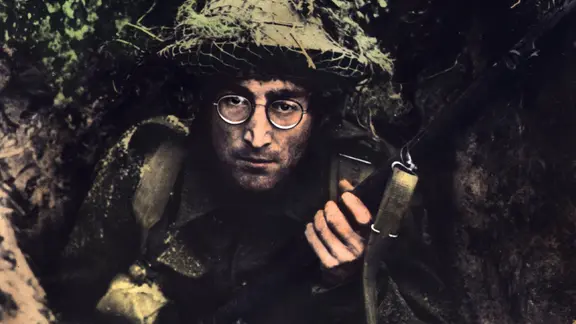 "Wie ich den Krieg gewann" bleibt der einzige Film, in dem John Lennon eine (kleine) Sprechrolle einnimmt. | IMAGO / United Archives John Lennon schaut mit Tarnuniform und Gewehr in der Hand in die Kamera