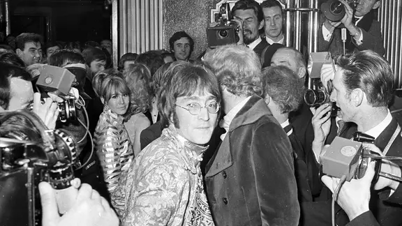 Auch bei der Londoner Premiere von "How I Won the War" trägt John Lennon (links Ehefrau Cynthia) die Nickelbrille, die er in seiner Filmrolle tragen musste. | IMAGO / United Archives International John Lennon und Ehefrau Cynthia (l.) bei der Premiere von "How I Won the War" 1967 in London