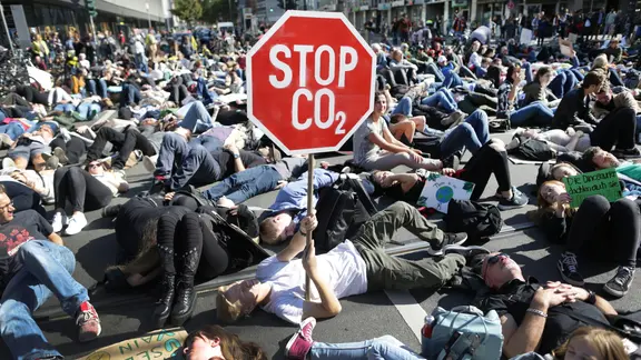 Teilnehmer einer Demonstration liegen auf einer Straßenkreuzung (Archivbild). Ein Demonstrant hält sein Plakat "Stop CO2" hoch. | dpa Teilnehmer einer Demonstration liegen auf einer Straßenkreuzung (Archivbild). Ein Demonstrant hält sein Plakat "Stop CO2" hoch.