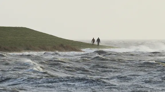 Menschen gehen bei einer Sturmflut an der Nordsee in Dagebuell spazieren | picture alliance / Caro Menschen gehen bei einer Sturmflut an der Nordsee in Dagebuell spazieren