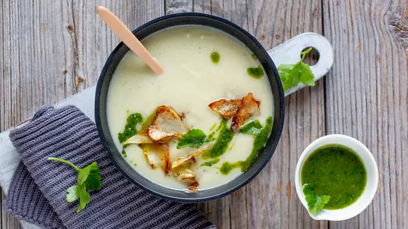 Eine Schüssel mit Wurzelcremesuppe, Pesto und Topinamburchips. | NDR/ZS Verlag, Claudia Timmann/ Eine Schüssel mit Wurzelcremesuppe, Pesto und Topinamburchips.