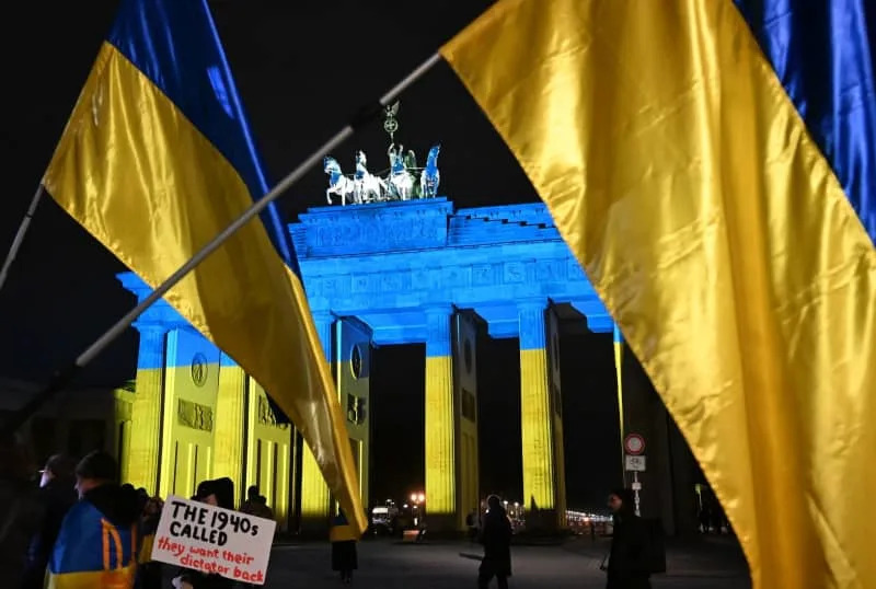 The Brandenburg Gate is illuminated in the colors of the Ukraine flag as participants gather to mark the fourth anniversary of the outbreak of the war in Ukraine. Markus Lenhardt/dpa