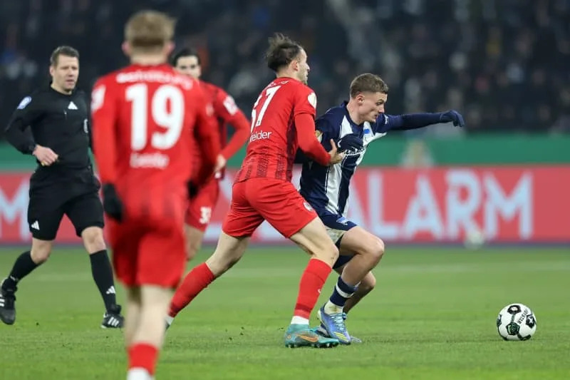 Freiburg's Max Rosenfelder and Hertha's Michael Cuisance battle for the ball during the German DFB Cup quarter-final soccer match between Hertha BSC and SC Freiburg at Olympiastadion. Andreas Gora/dpa