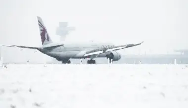 Qatar Airways aircraft on snow-covered runway during severe winter weather at Berlin Airport