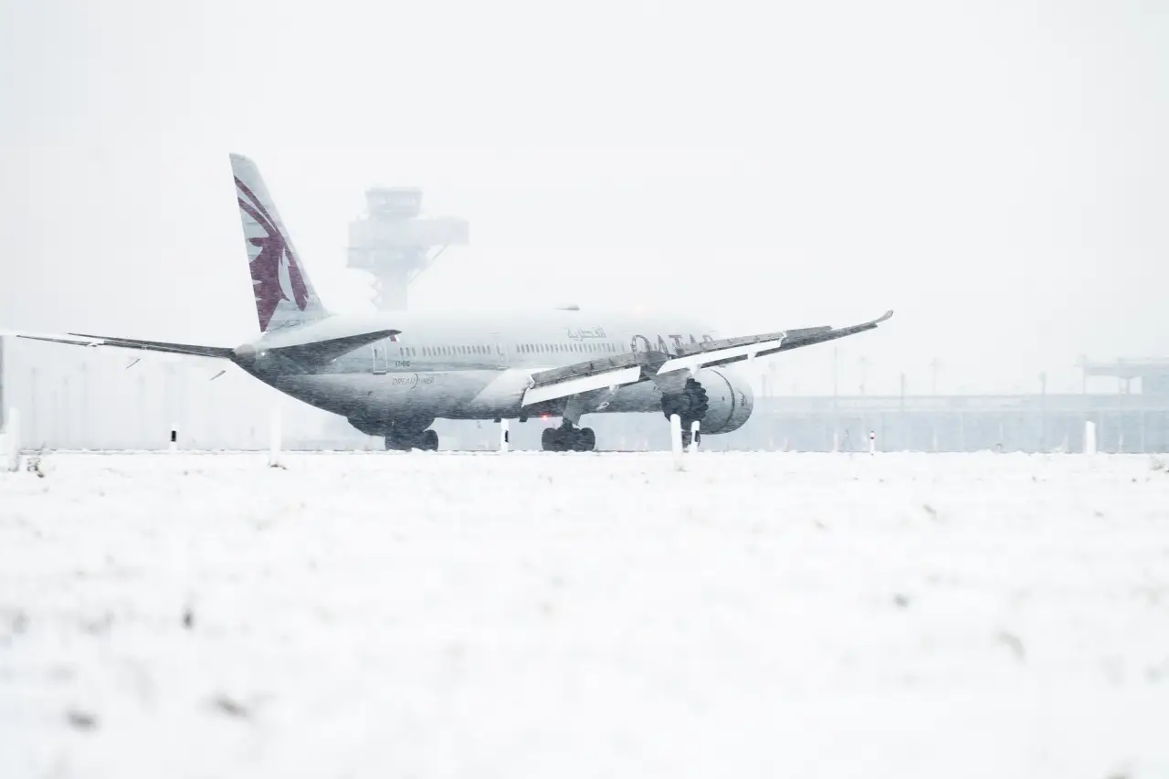 Qatar Airways aircraft on snow-covered runway during severe winter weather at Berlin Airport