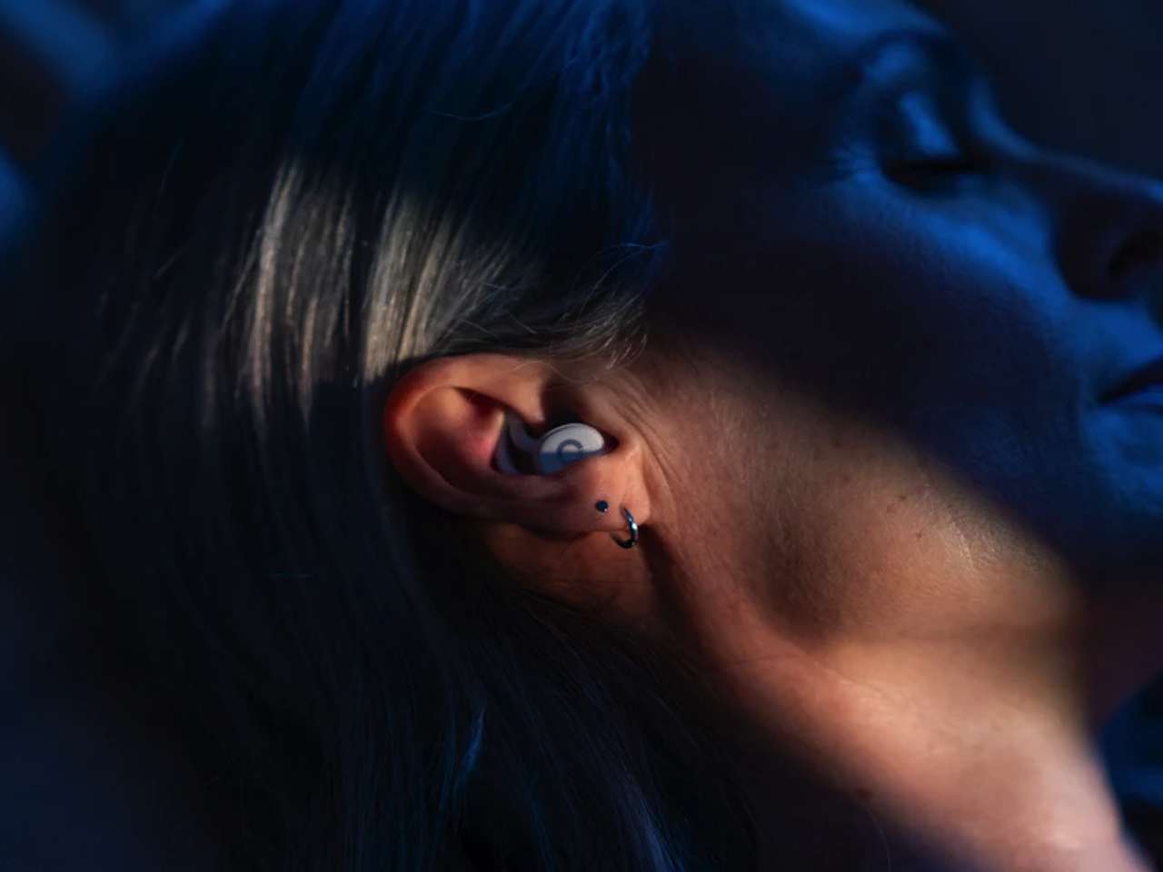 Ear with sleepbuds visible.