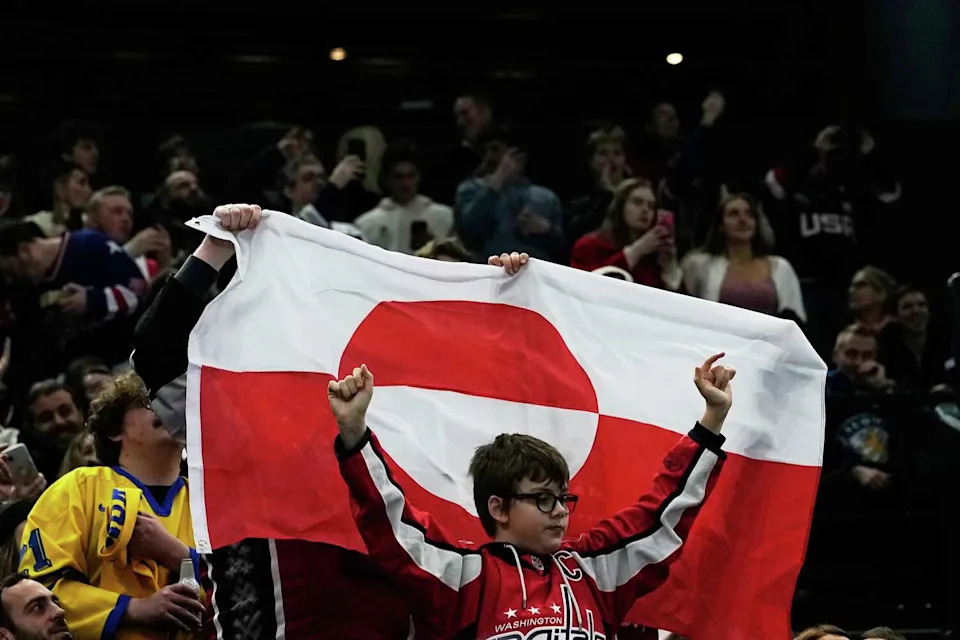 Fans hold a Greenland national flag before a preliminary round match of men's ice hockey between United States and Denmark at the 2026 Winter Olympics, in Milan, Italy, Saturday, Feb. 14, 2026. (AP Photo/Petr David Josek) (Petr David Josek/Associated Press)
