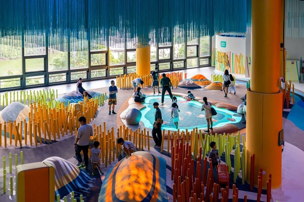 Indoor playground with vibrant designs and children playing among colorful structures.