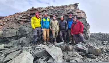 Researchers stand on a rocky slope in northeast Greenland after a fossil field expedition on Ymer Island near Mount Celsius.