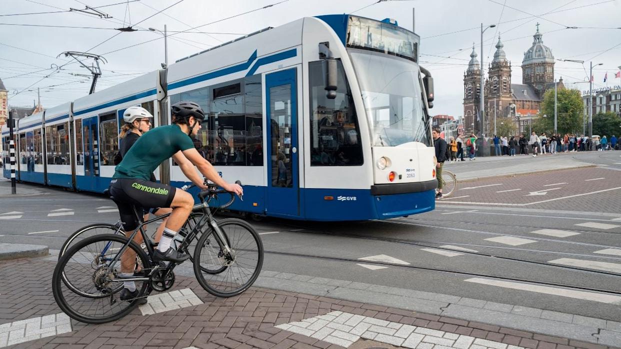 AMSTERDAM NETHERLANDS - OCTOBER 29, 2022, a man on a bicycle on a central street in the city on a road with a traffic tram
