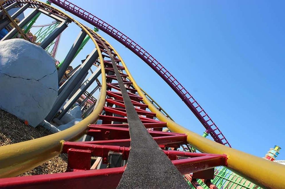 View from a colorful roller coaster track curving under a clear blue sky.