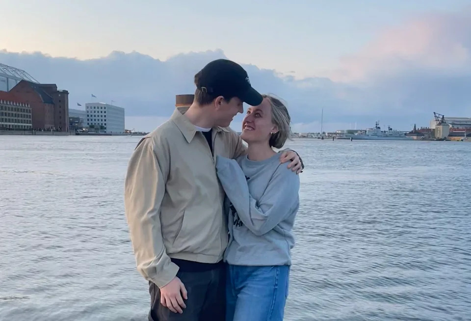 Amanda and her boyfriend look into each other's eyes while standing near a large body of water.