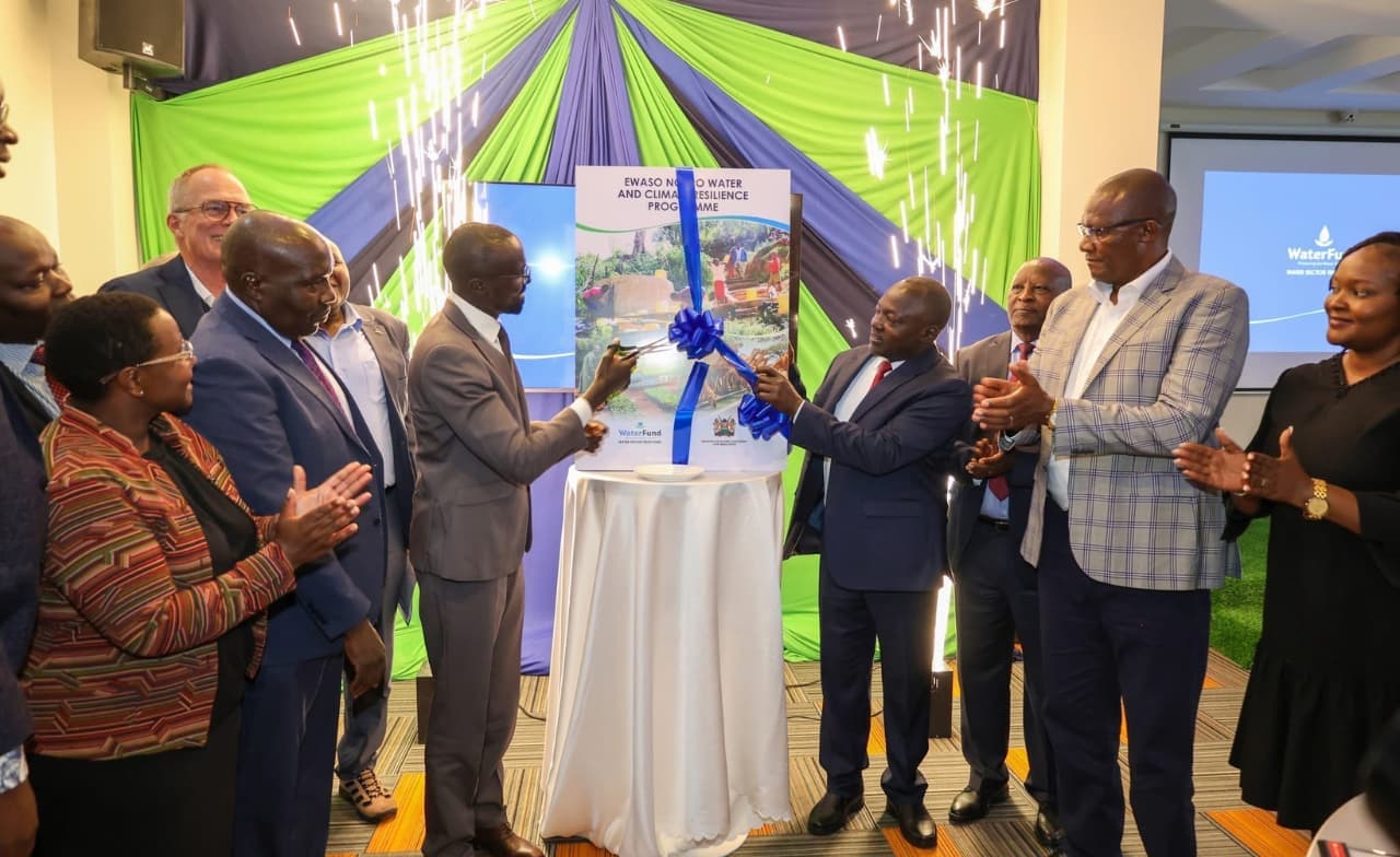 Officials cut a blue ribbon to launch the Ewaso Ng'iro Water and Climate Resilience Programme, with sparklers and a green-and-blue backdrop behind them.