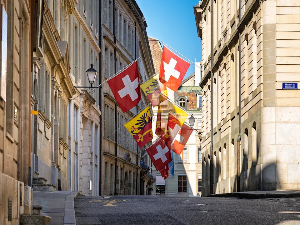 Swiss and Geneva flags hang above a narrow stone street