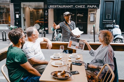 Ali Akbar charla con unos clientes habituales en una terraza del barrio Latino de París.