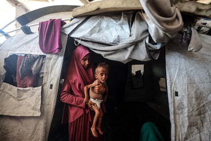 Hidaya, de 31 años, sostiene a su hijo Mohamed al-Mutawaq, de 18 meses, en su tienda en el campo de refugiados de al Shati, en la ciudada de Gaza, el pasado 25 de julio. 