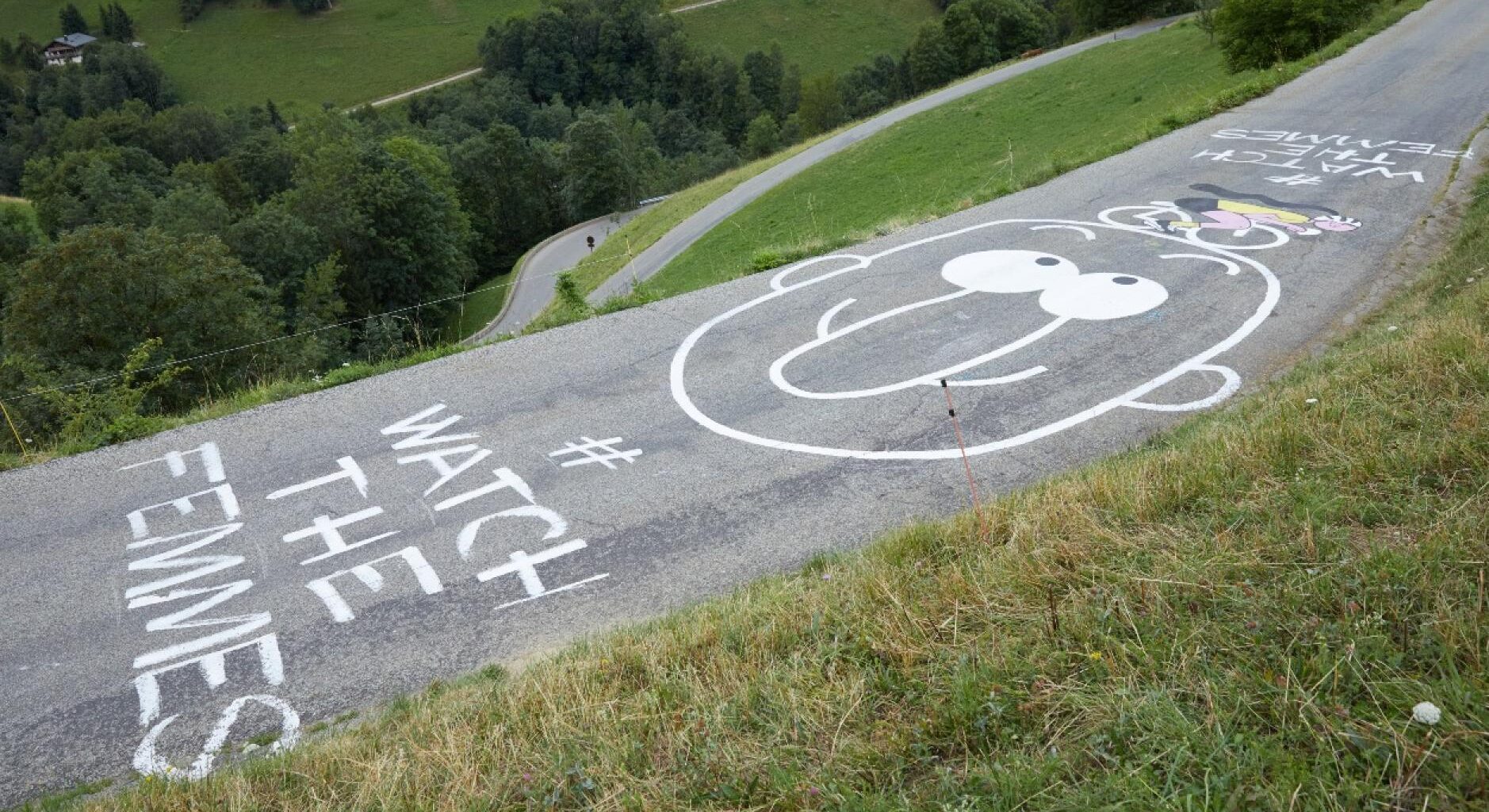 un grafiti en la carretera que dice watch the femmes junto al dibujo de una cara con nariz con forma de pene