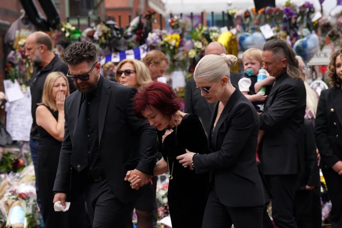 La familia de Ozzy Osbourne (de izquierda a derecha): Jack, Sharon y Kelly Osbourne, observan los mensajes y ofrendas florales depositadas en el banco del puente Black Sabbath en la calle Broad, en Birmingham, en memoria del líder de Black Sabbath, Ozzy Osbourne, mientras su cuerpo es trasladado de regreso a su ciudad natal para una procesión tras su fallecimiento la semana pasada, a los 76 años.