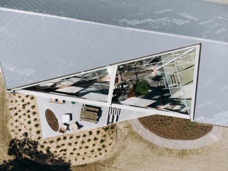 Un recorte triangular en el volumen original crea un patio interior que inunda la casa de luz natural, a la vez que genera una fluida transición hacia el exterior