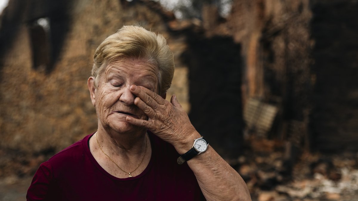 Una vecina de Castrocalbón, junto a una vivienda que ha sido destruida por los incendios.